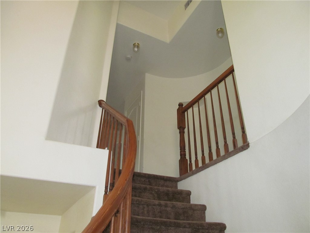 8701 Crescent Ridge Lane Las Vegas, NV 89134 - Photo 16 of 28 A graceful curved staircase with rich wooden banisters invites movement to the upper level.