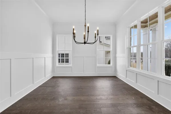 an empty room with wooden floor exposed radiator and windows