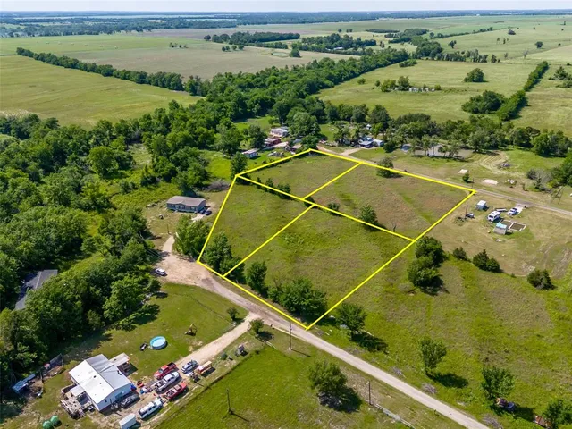 an aerial view of a residential houses with outdoor space and trees
