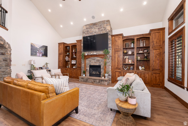 687 South 2080th Street East Springville, UT 84663 - Photo 13 of 149 Vaulted living area featuring a stone fireplace, built-in wooden cabinetry with shelving, wood-finish flooring, and recessed lighting