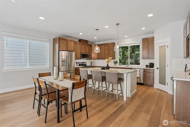 a kitchen with stainless steel appliances a dining table chairs stove refrigerator and cabinets