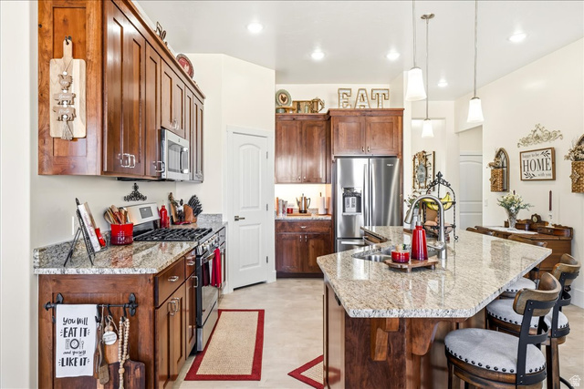 357 East Main Street Enterprise, UT 84725 - Photo 18 of 71 Kitchen featuring stainless steel appliances, light stone countertops, a center island with sink, and a breakfast bar area