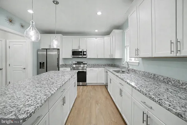 a large kitchen with stainless steel appliances granite countertop a stove a sink and a refrigerator