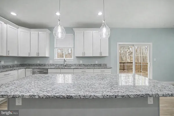 a kitchen with granite countertop white cabinets and a sink