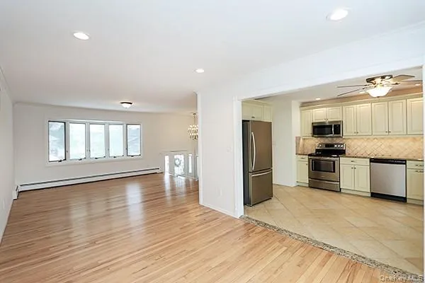a large kitchen with a refrigerator a sink dishwasher and a stove with wooden floor