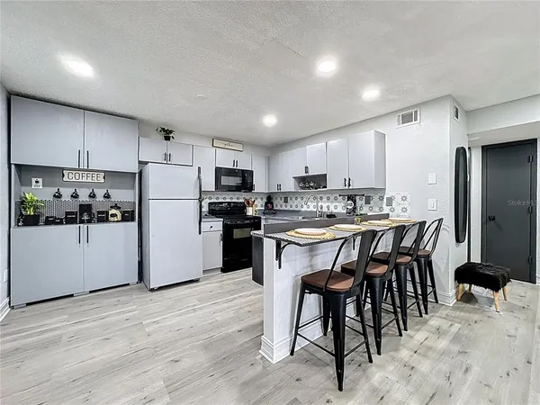 a kitchen with stainless steel appliances granite countertop a refrigerator stove a sink dishwasher and a refrigerator with wooden floor