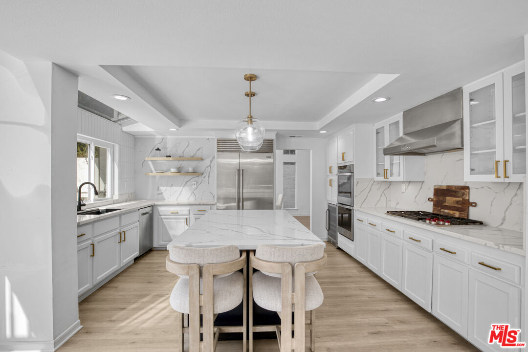 19668 Pine Valley Way Porter Ranch, CA 91326 - Photo 12 of 52 a large kitchen with granite countertop a center island a stove a dining table and chairs