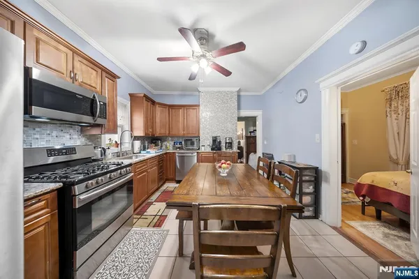 a kitchen with stainless steel appliances granite countertop a refrigerator a stove top oven a sink a dining table and chairs
