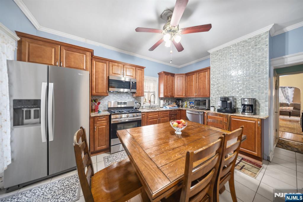 409 Hamilton Street Harrison, NJ 07029 - Photo 12 of 44 a kitchen with stainless steel appliances granite countertop a refrigerator a stove top oven a sink a dining table and chairs