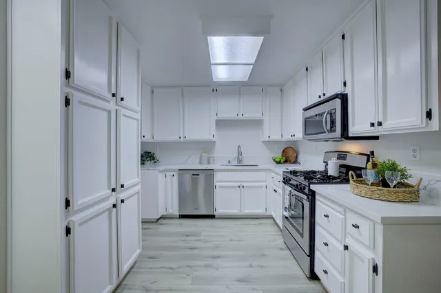 a kitchen with stainless steel appliances granite countertop a stove top oven a sink dishwasher and a refrigerator with wooden cabinets