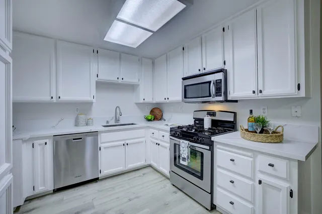 a kitchen with cabinets stainless steel appliances a sink and wooden floor
