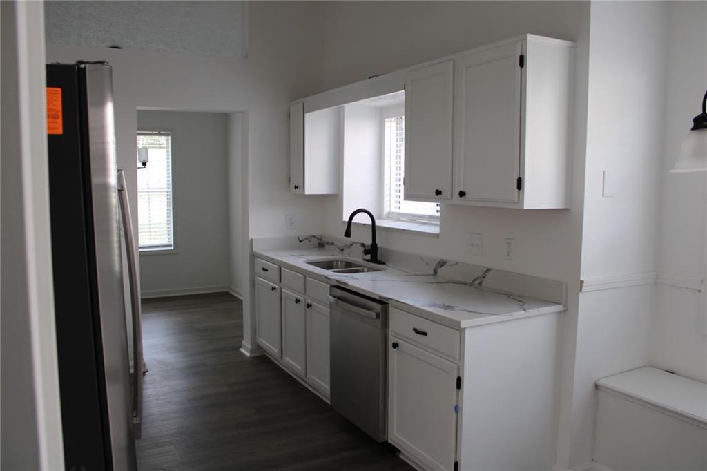 3389 Lochness Lane Powder Springs, GA 30127 - Photo 10 of 48 a kitchen with stainless steel appliances granite countertop a sink and dishwasher with wooden floor