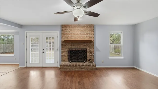 a view of an empty room with wooden floor fireplace and a window
