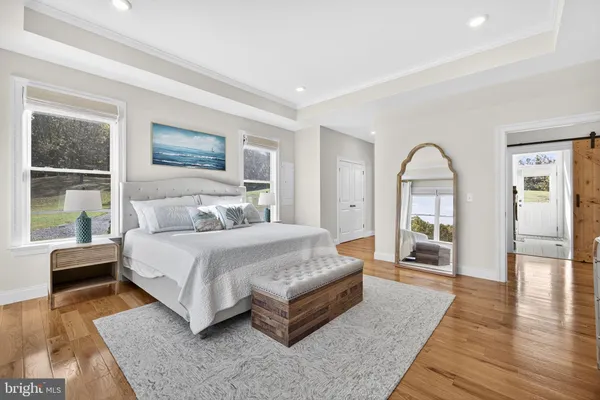 a spacious bedroom with a balcony a bed and wooden floor
