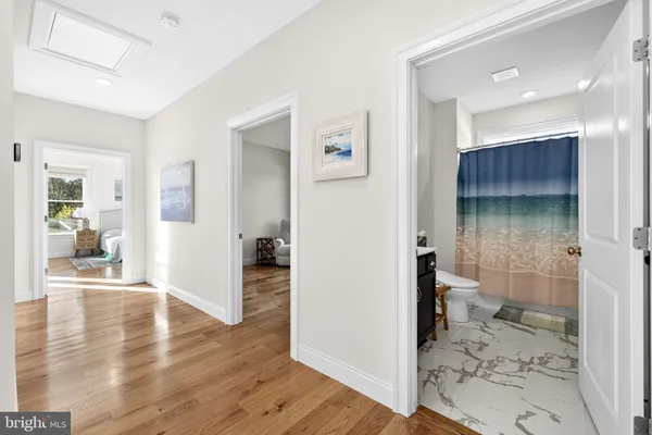 a view of a hallway with wooden floor and a bathroom