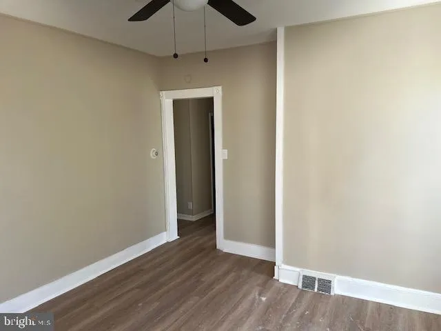 an empty room with wooden floor a ceiling fan and closet