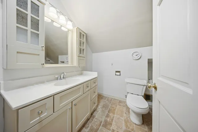 a bathroom with a granite countertop toilet sink and mirror