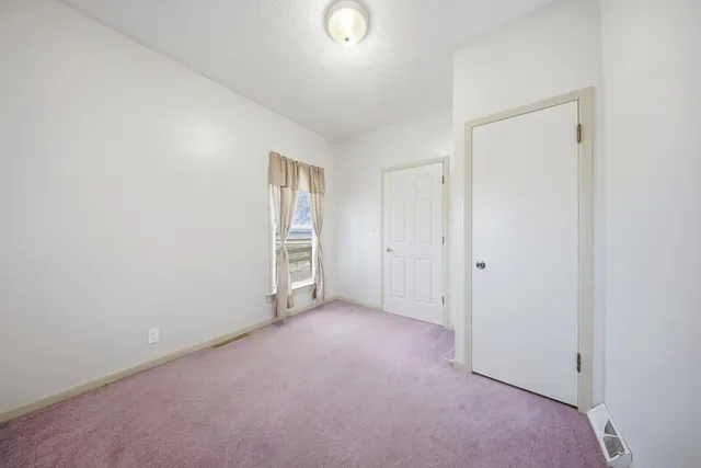 an empty room with closet and windows
