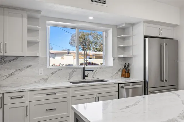 a kitchen with stainless steel appliances a refrigerator a stove a sink and chairs