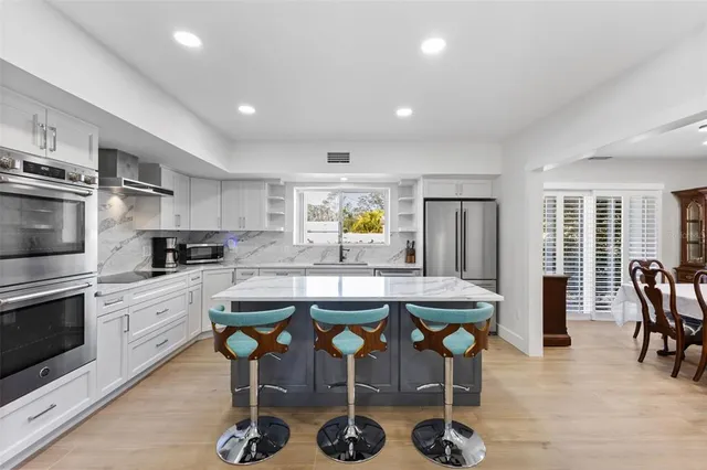 a kitchen with stainless steel appliances kitchen island granite countertop a table chairs sink and cabinets