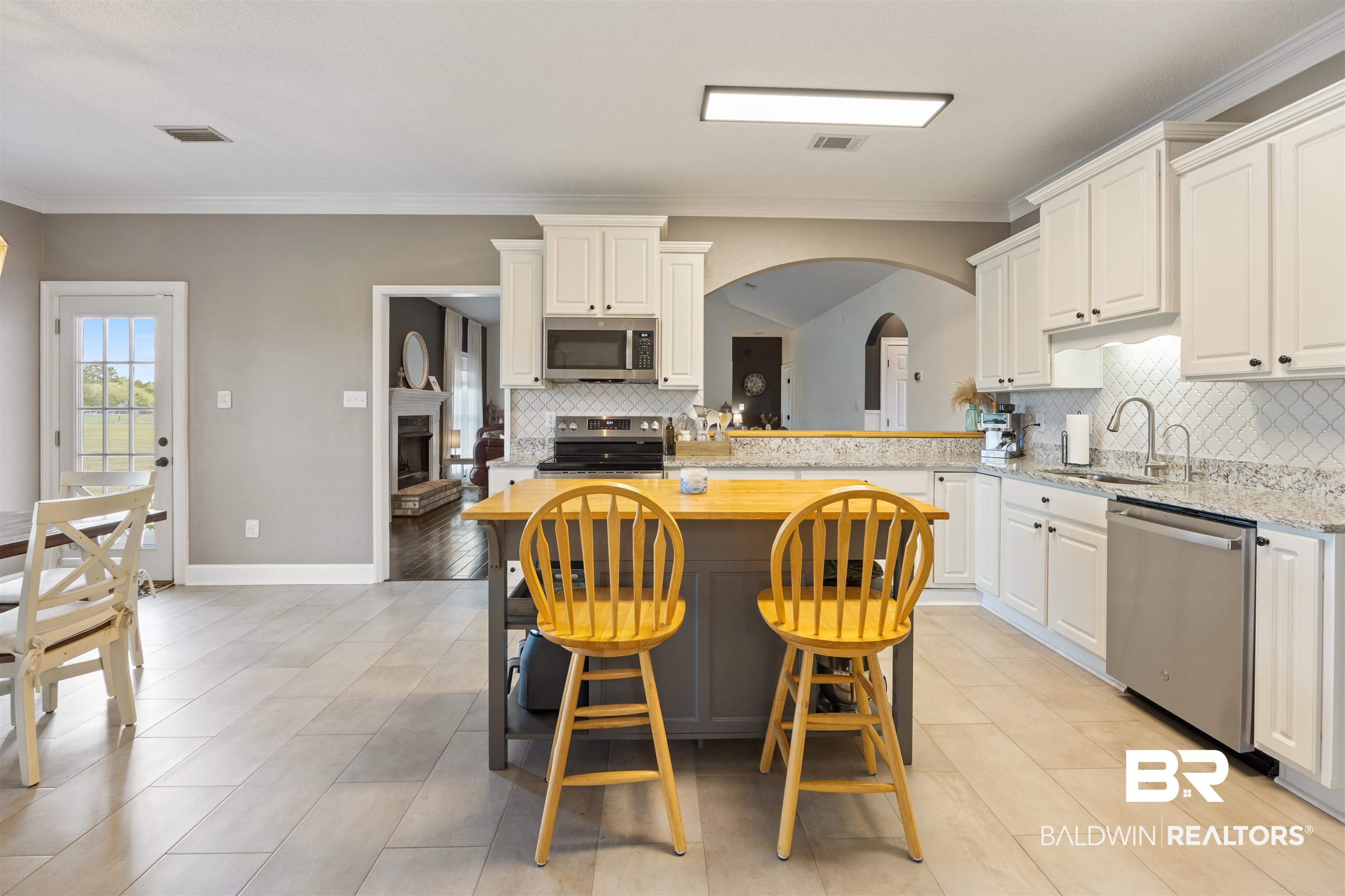 9855 Stucki Road Elberta, AL 36530 - Photo 28 of 54 Kitchen with arched walkways, crown molding, backsplash, stainless steel appliances, and a kitchen island