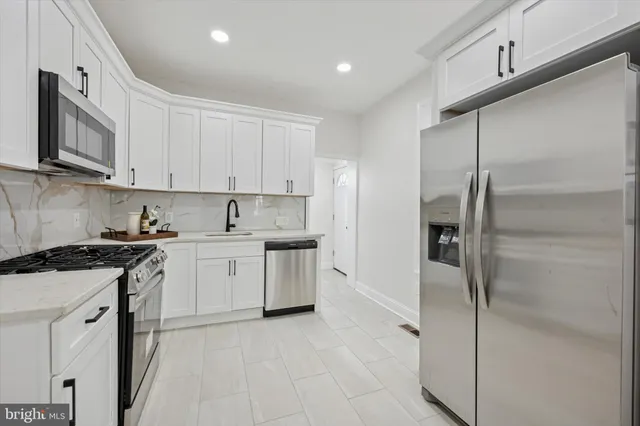 a kitchen with stainless steel appliances granite countertop a refrigerator a stove and white cabinets