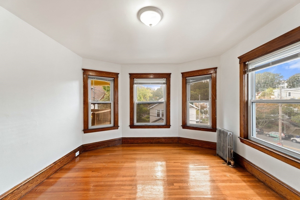 25 Tip Top Street, Unit 2 Boston, MA 02135 - Photo 12 of 35 a view of an empty room with a window and wooden floor
