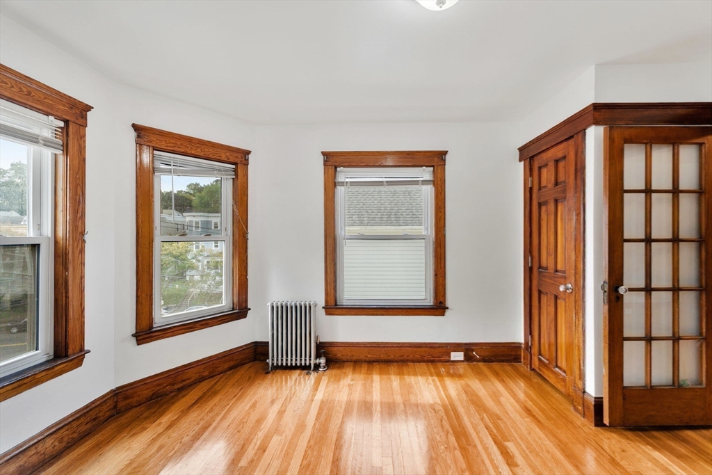 25 Tip Top Street, Unit 2 Boston, MA 02135 - Photo 13 of 35 an empty room with wooden floor and windows