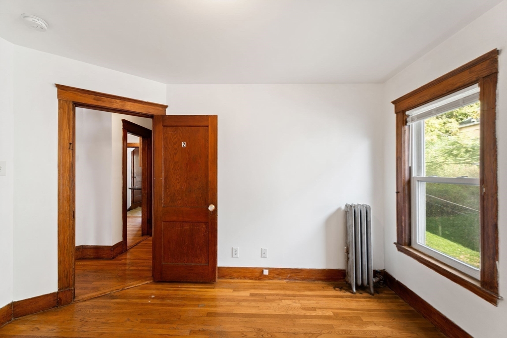 25 Tip Top Street, Unit 2 Boston, MA 02135 - Photo 14 of 35 a view of an empty room with wooden floor and a window