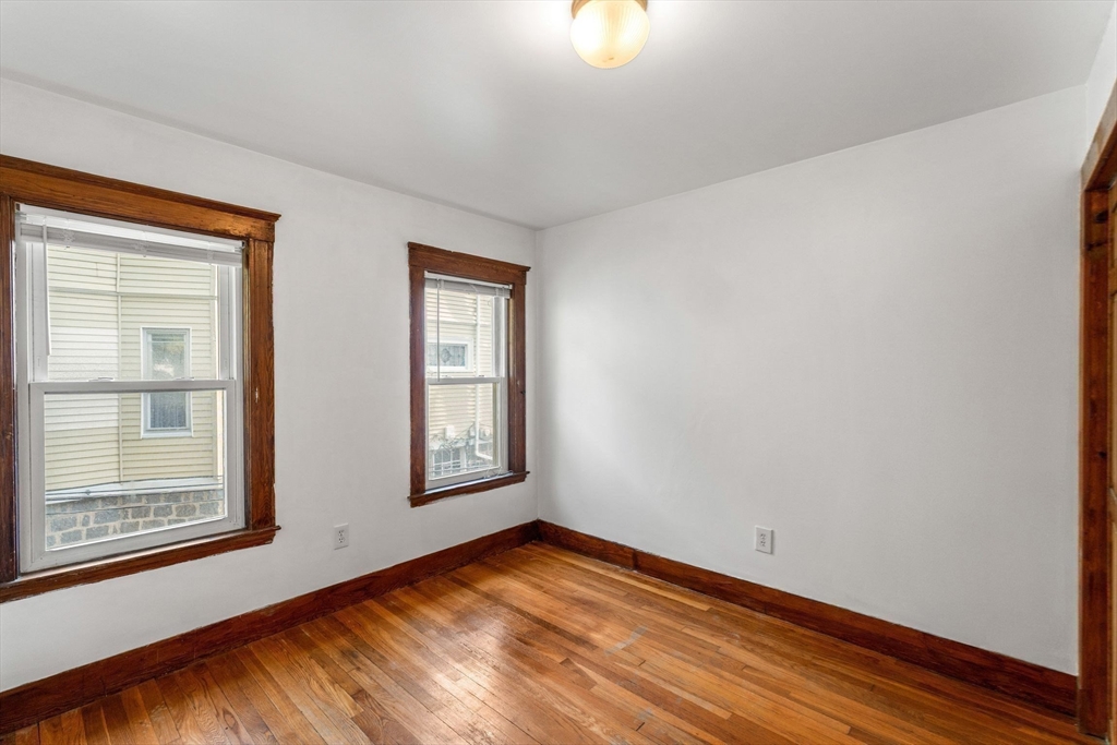 25 Tip Top Street, Unit 2 Boston, MA 02135 - Photo 16 of 35 a view of an empty room with wooden floor and a window