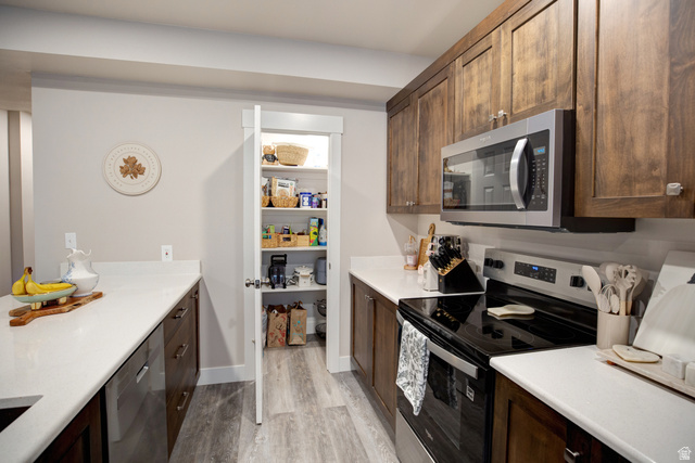 983 South 950 West Provo, UT 84601 - Photo 31 of 56 Kitchen featuring wood-finish cabinetry, light countertops, and a full-size electric range with an overhead microwave