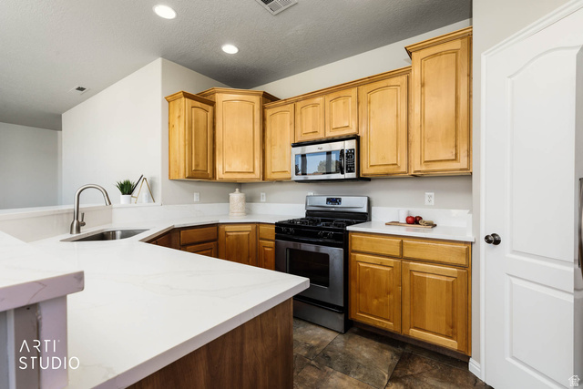2158 Balboa Way St. George, UT 84770 - Photo 9 of 40 Kitchen with stainless steel appliances, a textured ceiling, light stone countertops, and recessed lighting