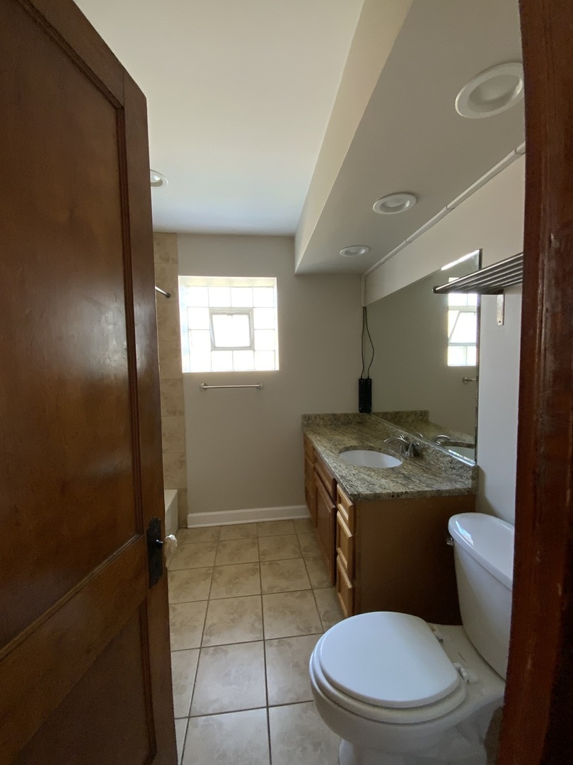 3116 North Elston Avenue, Unit 1 Chicago, IL 60618 - Photo 13 of 16 a bathroom with a granite countertop toilet sink and mirror