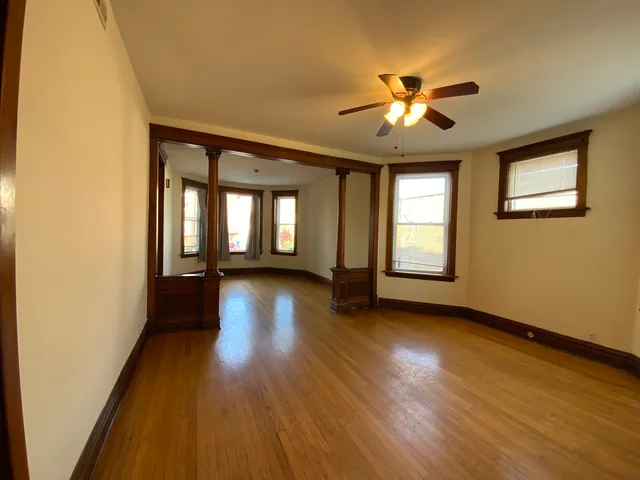 a view of empty room with wooden floor and fan