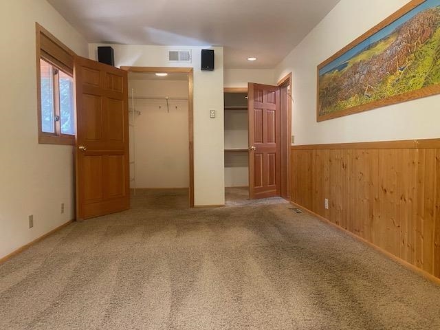 67 Hill Street Mammoth Lakes, CA 93546 - Photo 9 of 24 Unfurnished bedroom featuring light colored carpet and wooden walls, and large walk-in closet