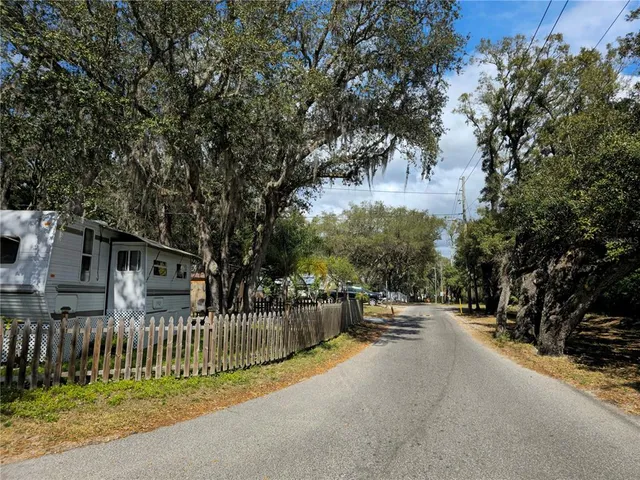 a view of a white house with a small yard and large tree