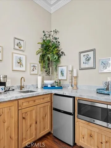 a view of an empty room with wooden floor and kitchen space