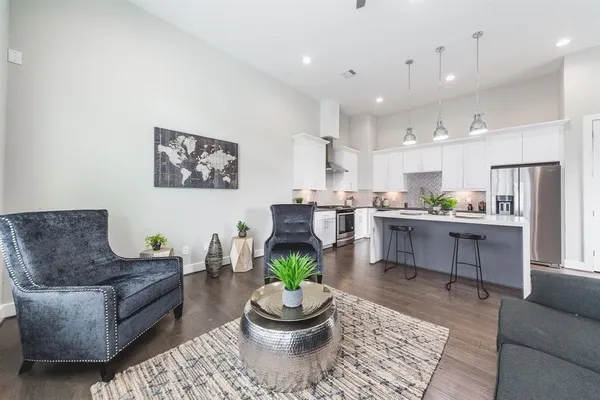 a living room with stainless steel appliances kitchen island granite countertop furniture and a rug