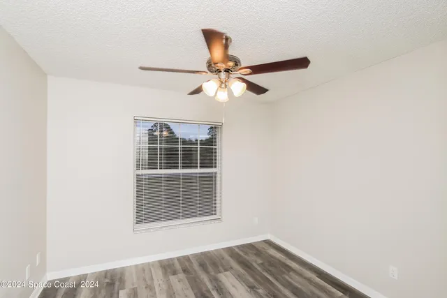 an empty room with a window and a fan