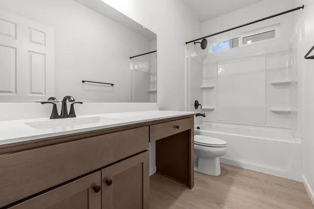 a bathroom with a bathtub shower sink vanity mirror and toilet