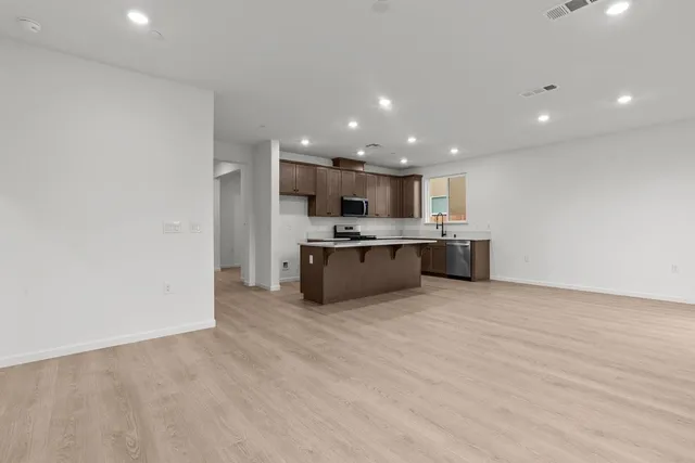 a view of kitchen with kitchen island stainless steel appliances a sink and a refrigerator