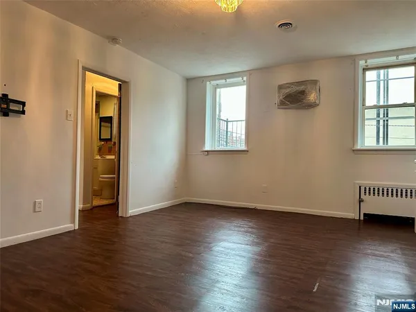 an empty room with wooden floor closet and windows