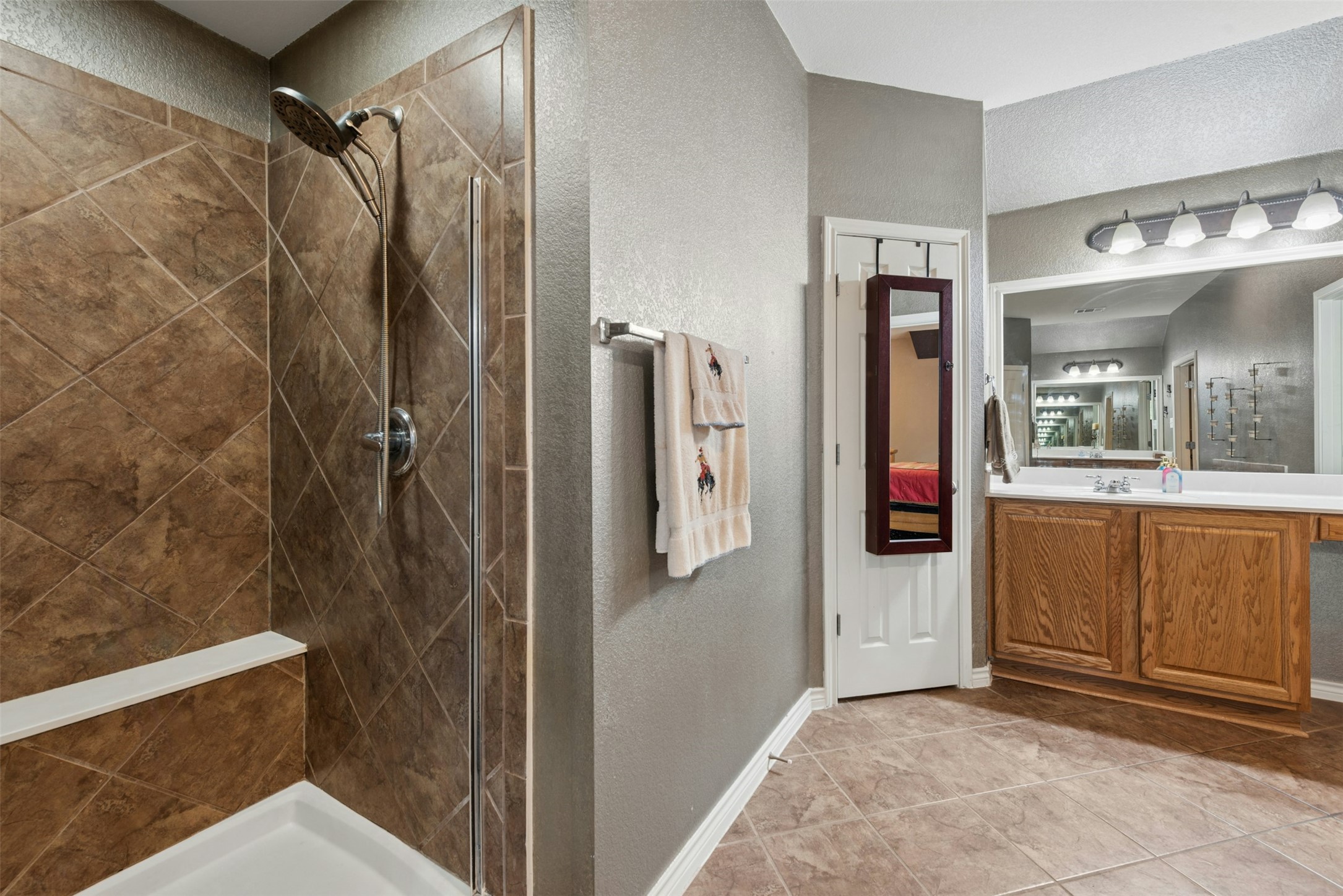 30013 Edgewood Drive Georgetown, TX 78628 - Photo 23 of 39 The bathroom features a tiled shower with a built-in bench, a vanity with wood cabinetry, and a large mirror