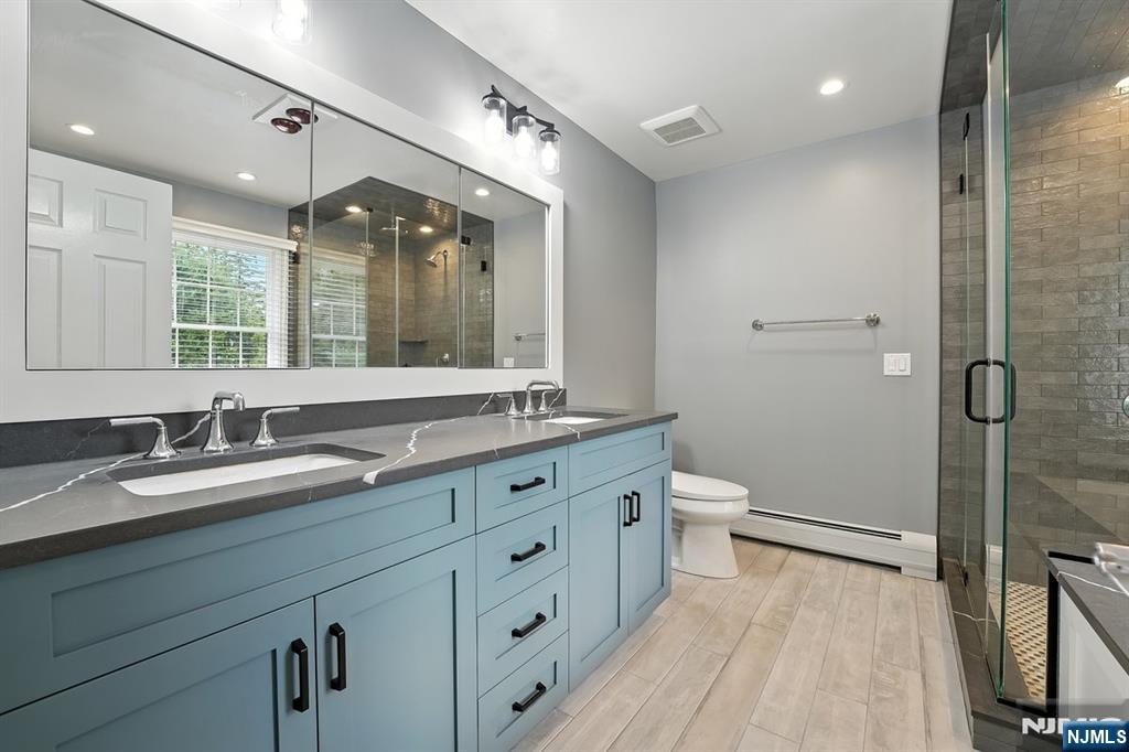 856 Stonewall Court Franklin Lakes, NJ 07417 - Photo 14 of 26 a bathroom with a double vanity sink toilet mirror and shower