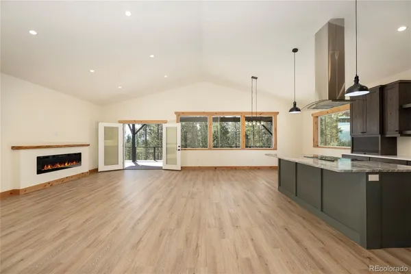 a large kitchen with stainless steel appliances a large counter top a wooden floors and a large window
