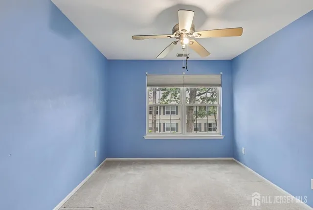 an empty room with a window and a ceiling fan