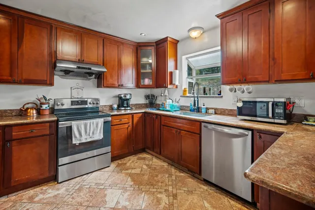 a kitchen with stainless steel appliances granite countertop wooden cabinets a stove top oven a sink and dishwasher