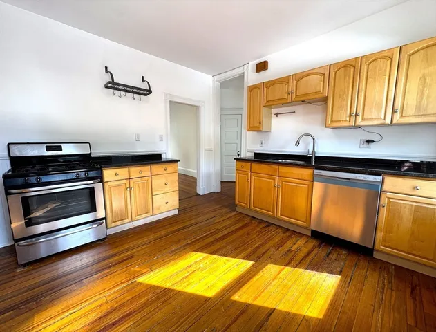 a kitchen with granite countertop a sink cabinets and stainless steel appliances