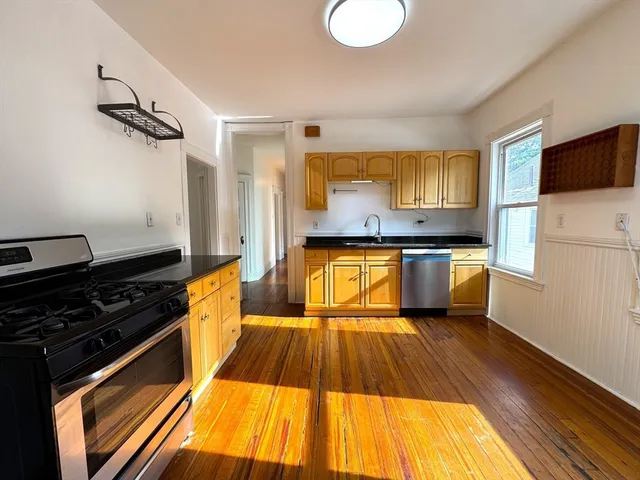 a kitchen with kitchen island granite countertop wooden floors and a sink