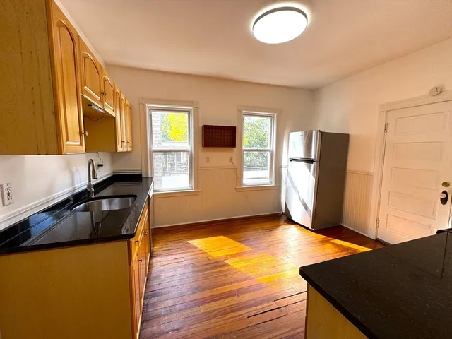 a kitchen with stainless steel appliances granite countertop a refrigerator a stove and a sink with wooden floor